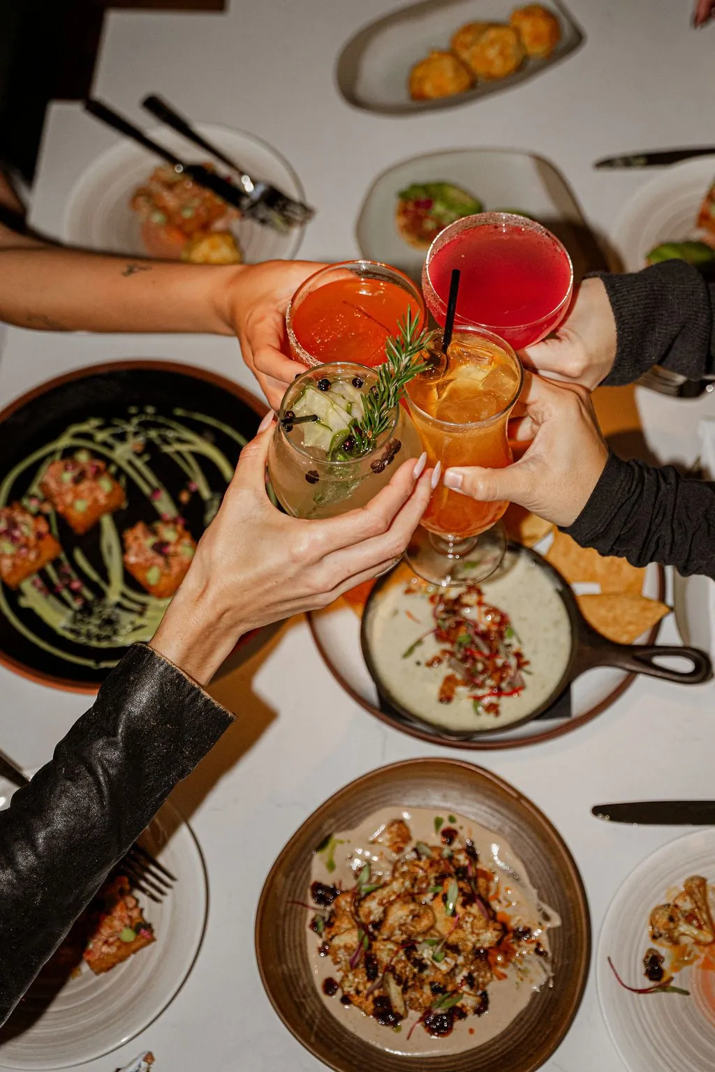 Friends raising glasses over a table of shared plates